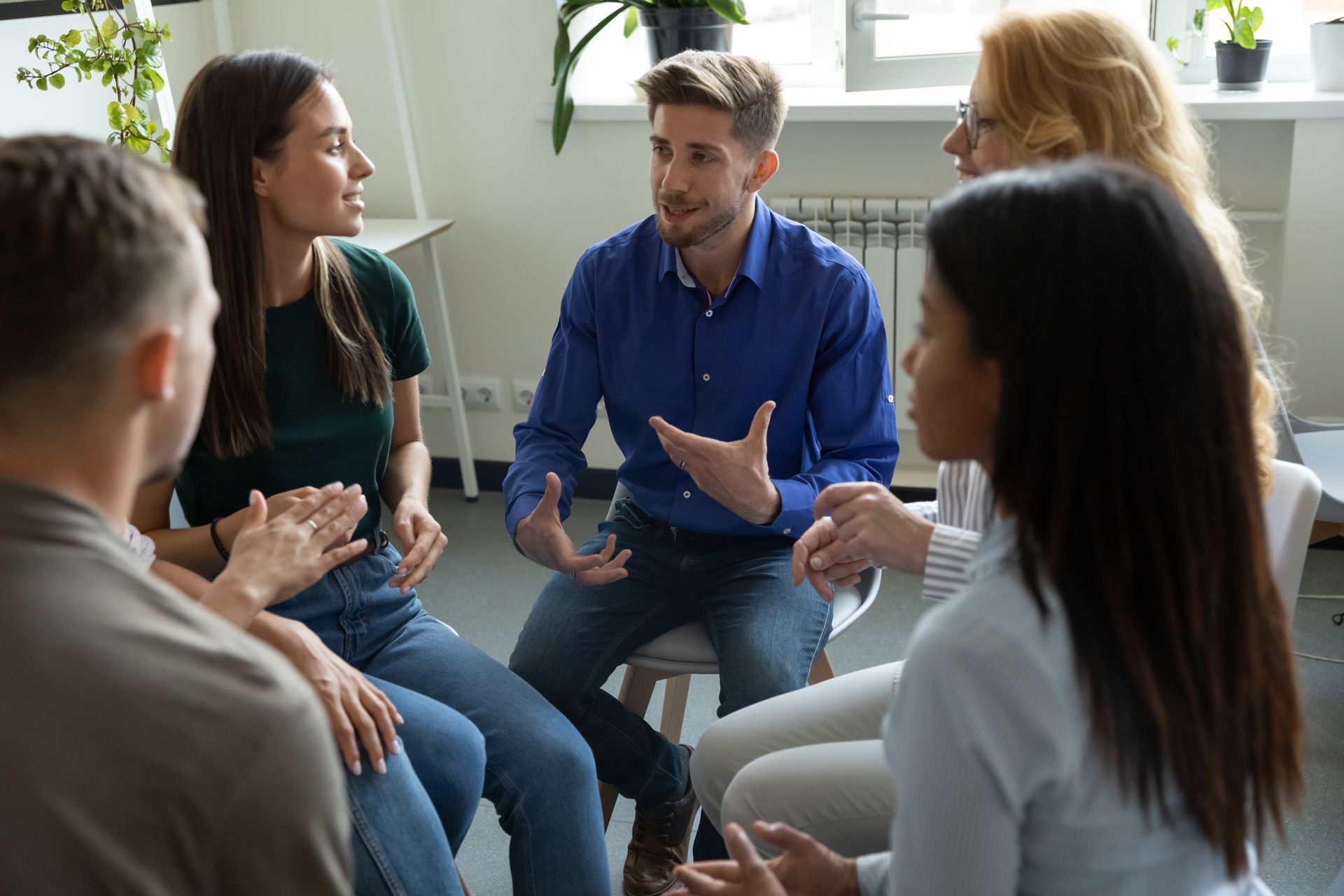 A group of people are sitting in a circle talking to each other.