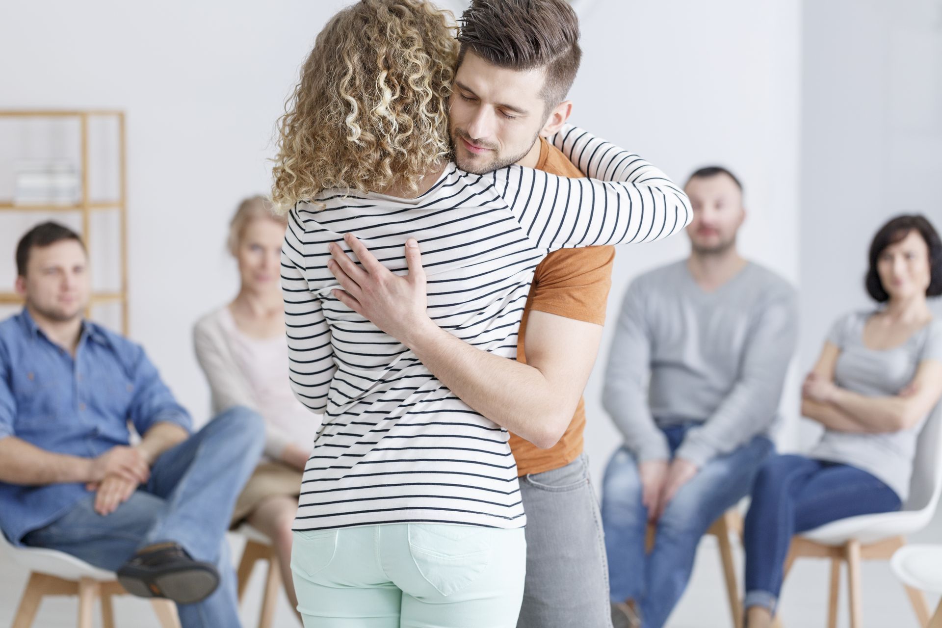 A man is hugging a woman in front of a group of people.