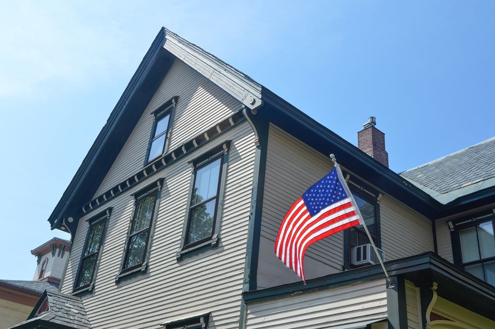 An american flag is flying on the side of a house
