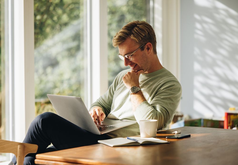 A man is sitting at a table using a laptop computer.