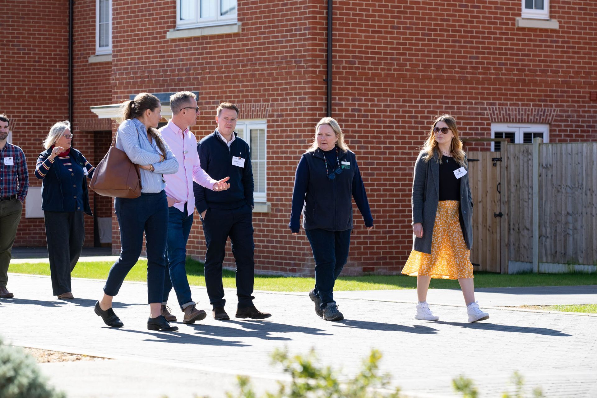 Group of people walking outside, likely on a tour, in front of brick buildings.