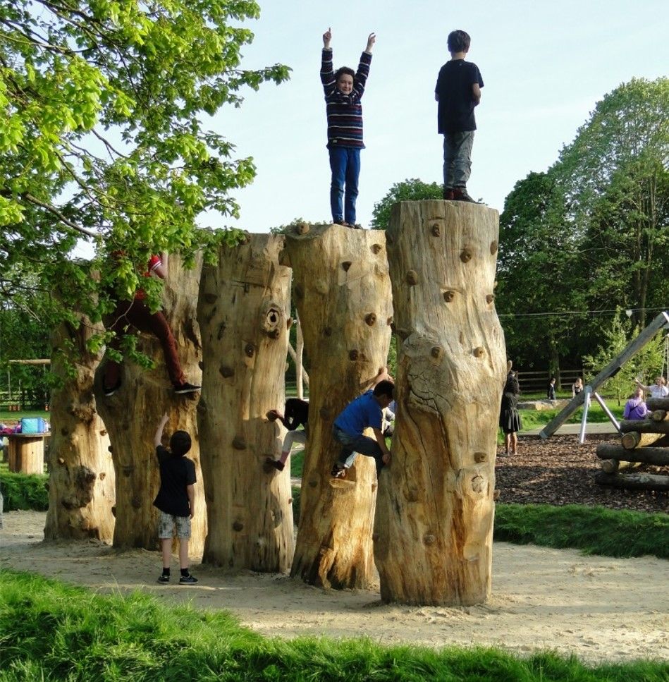 Children climb and play on a wooden climbing structure in a park.