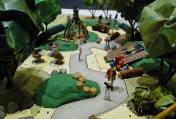 Miniature park scene with figures walking a path, trees, and a shelter.