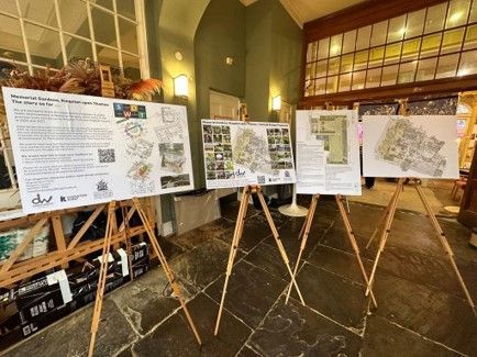 Three posters on easels displayed indoors, showcasing architectural plans.