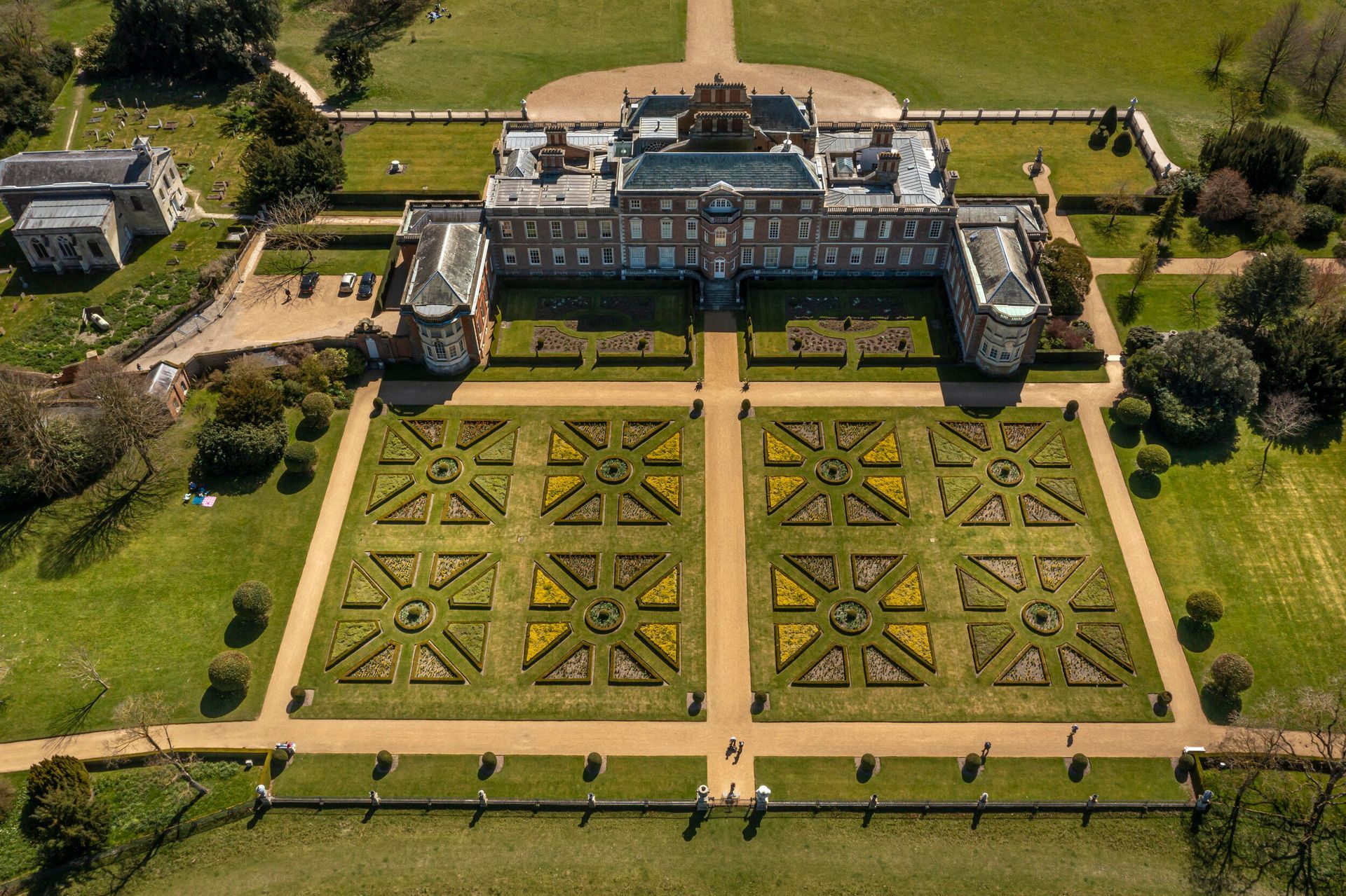 Aerial view of Kensington Palace and gardens in London, with symmetrical flowerbeds and green lawns.
