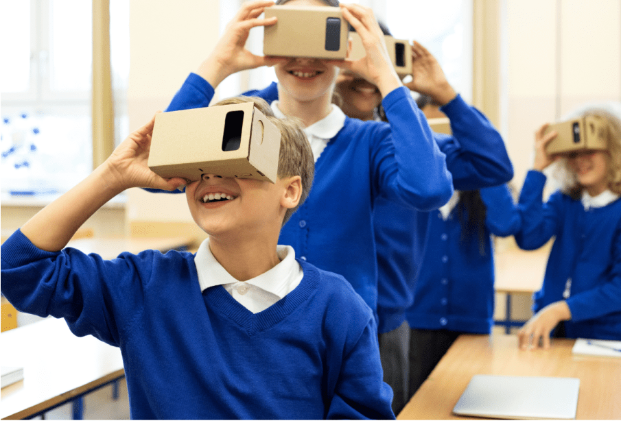 School children wearing VR headsets, smiling, in a classroom.