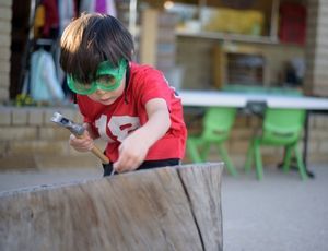 Montessori child hammering wood with focus, showing persistence and independence in work.