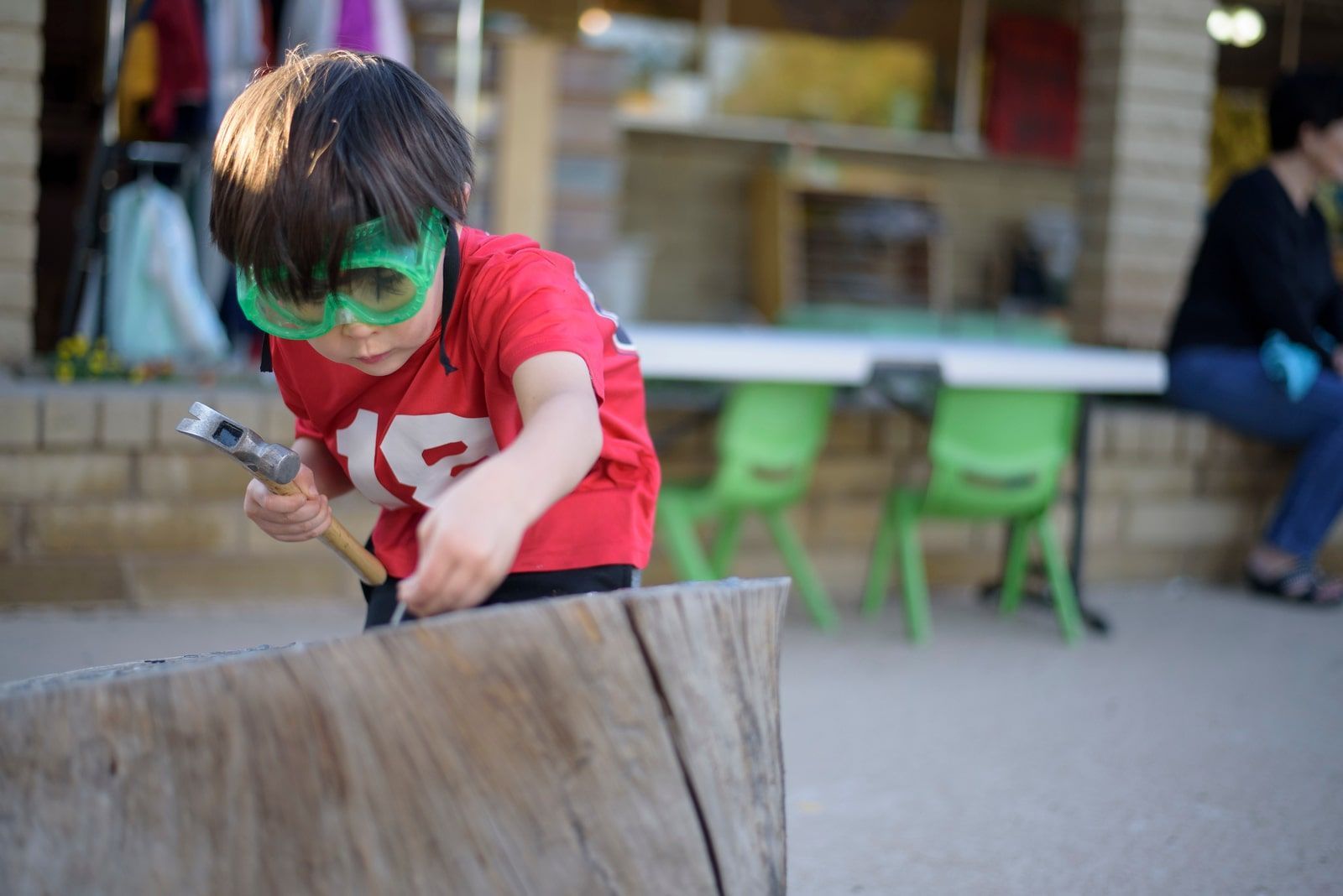 Montessori child hammering wood with focus, showing persistence and independence in work.