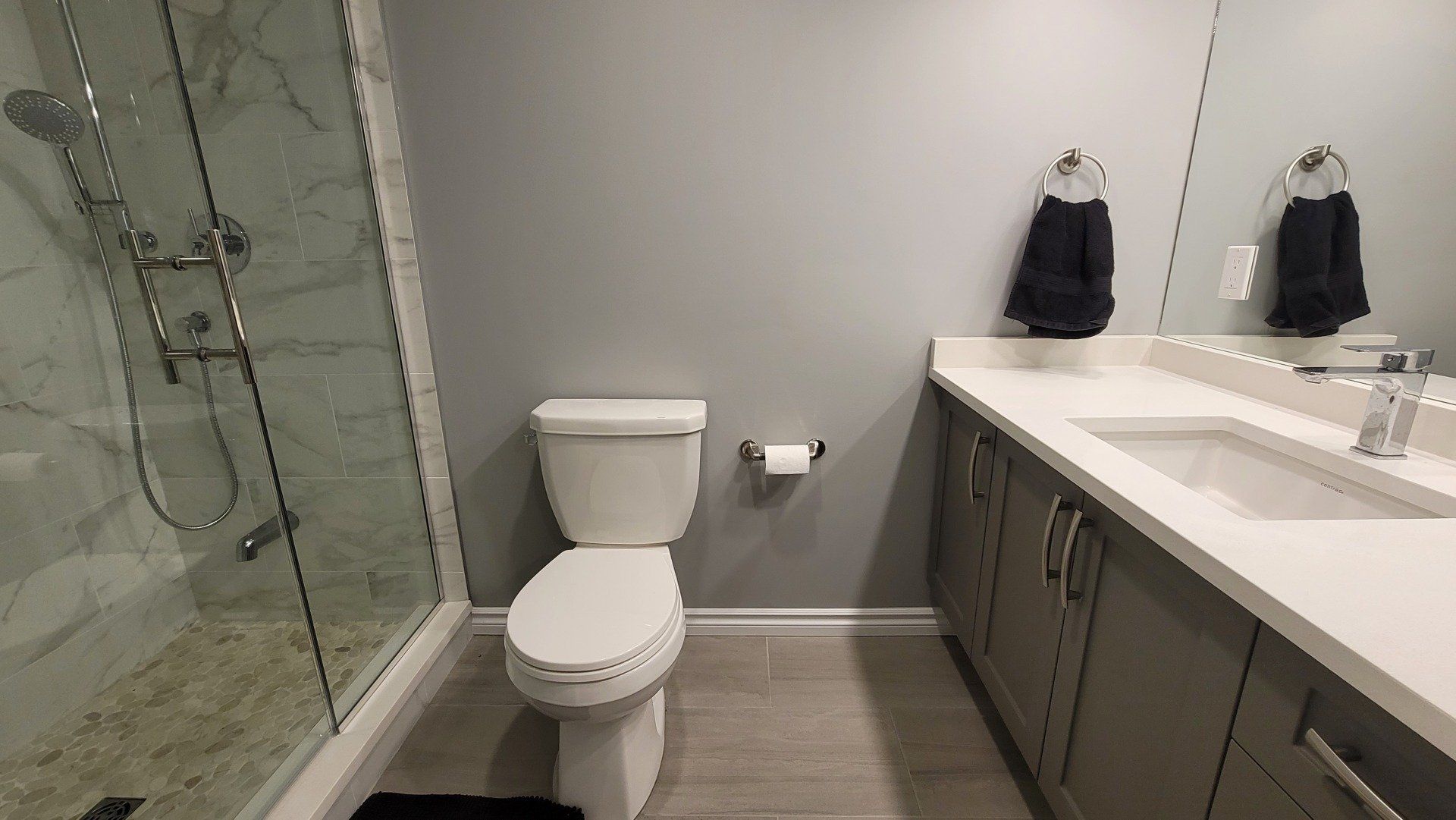 A bathroom with a toilet , sink and shower.