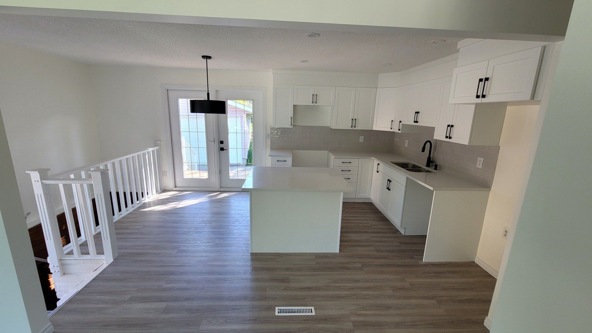 A kitchen with white cabinets and a large island in the middle of the room.