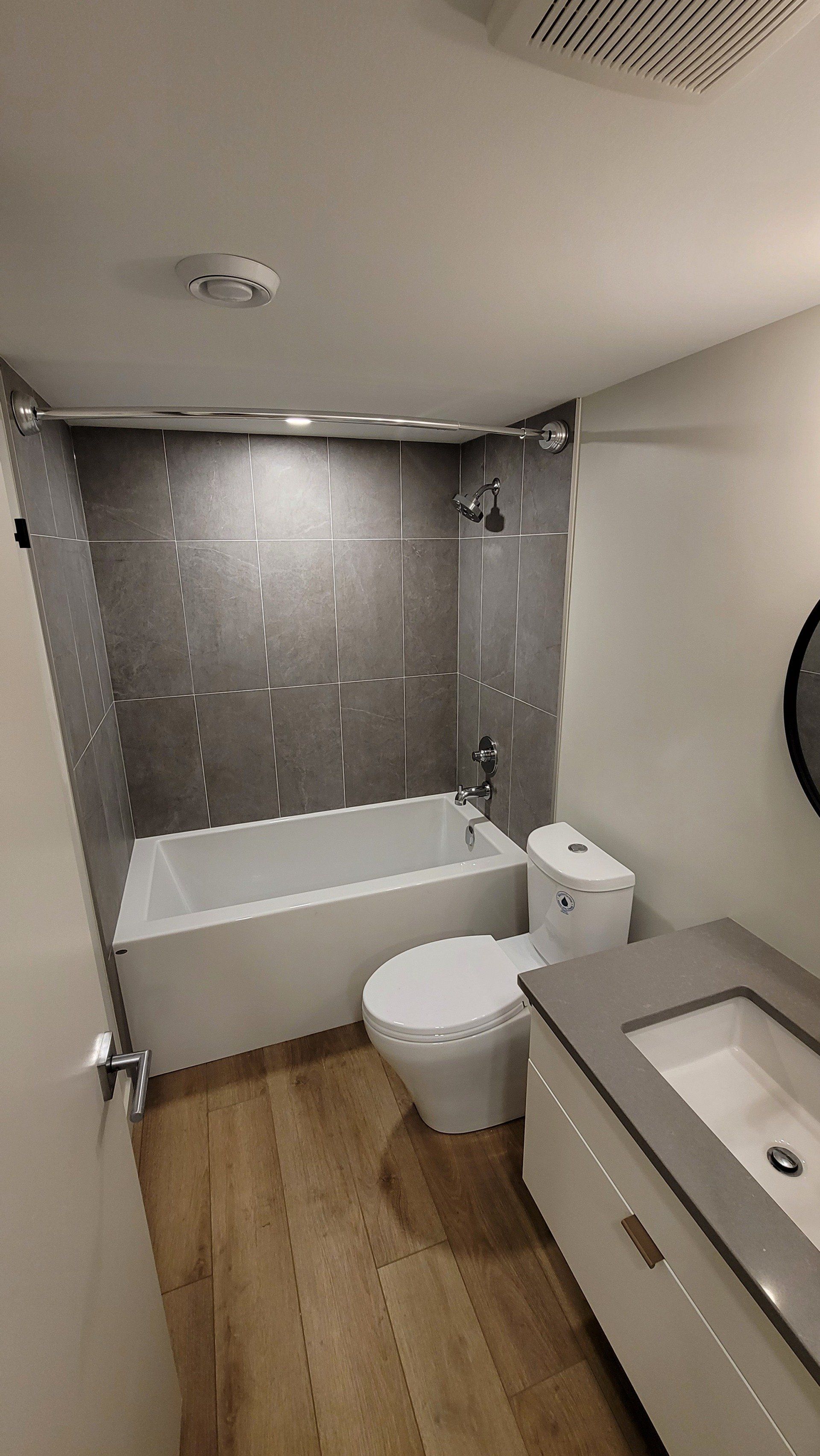 A bathroom with a tub , toilet , sink and shower.