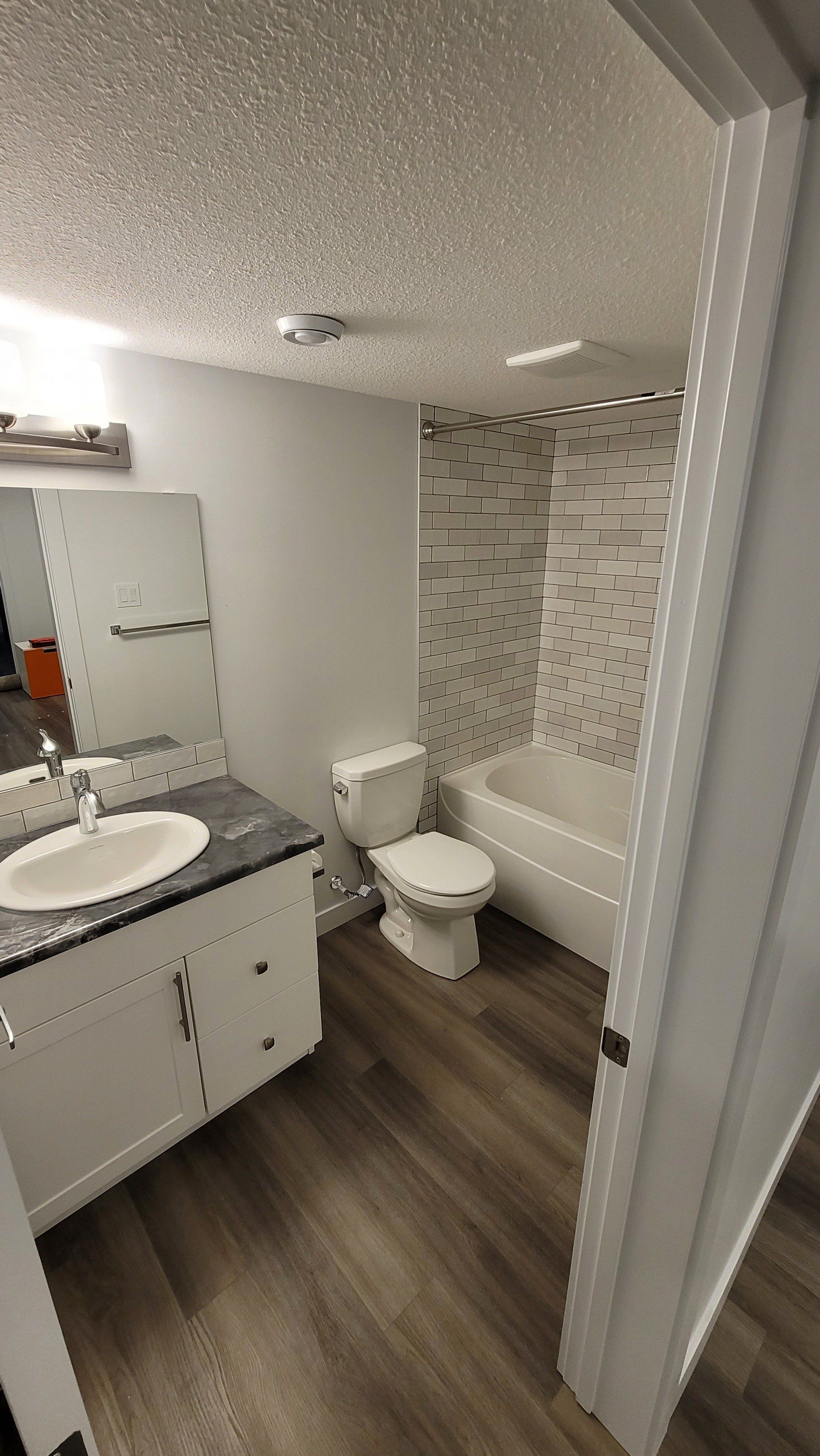 A bathroom with a sink , toilet , bathtub and mirror.