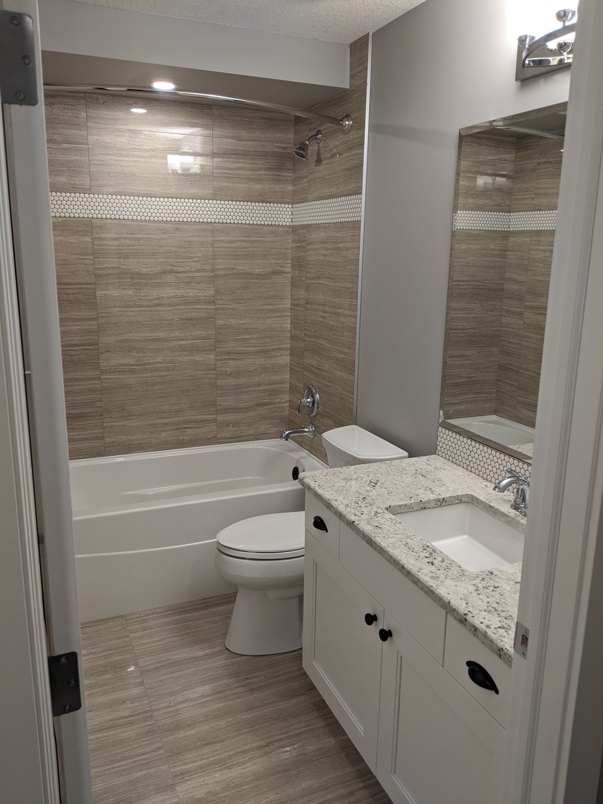 A bathroom with a toilet , sink , bathtub and mirror.
