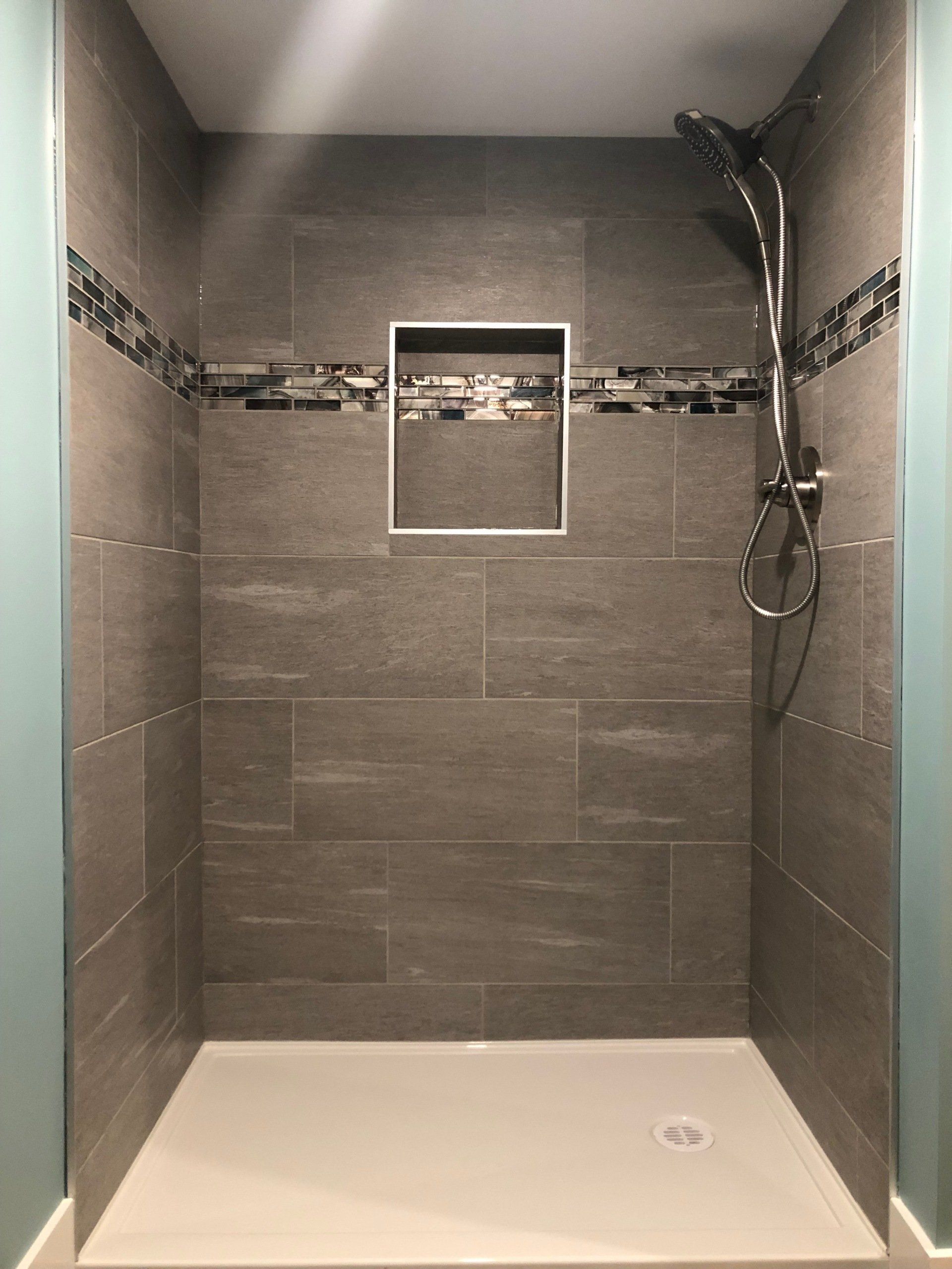 A shower with a shower head and a shelf on the wall.