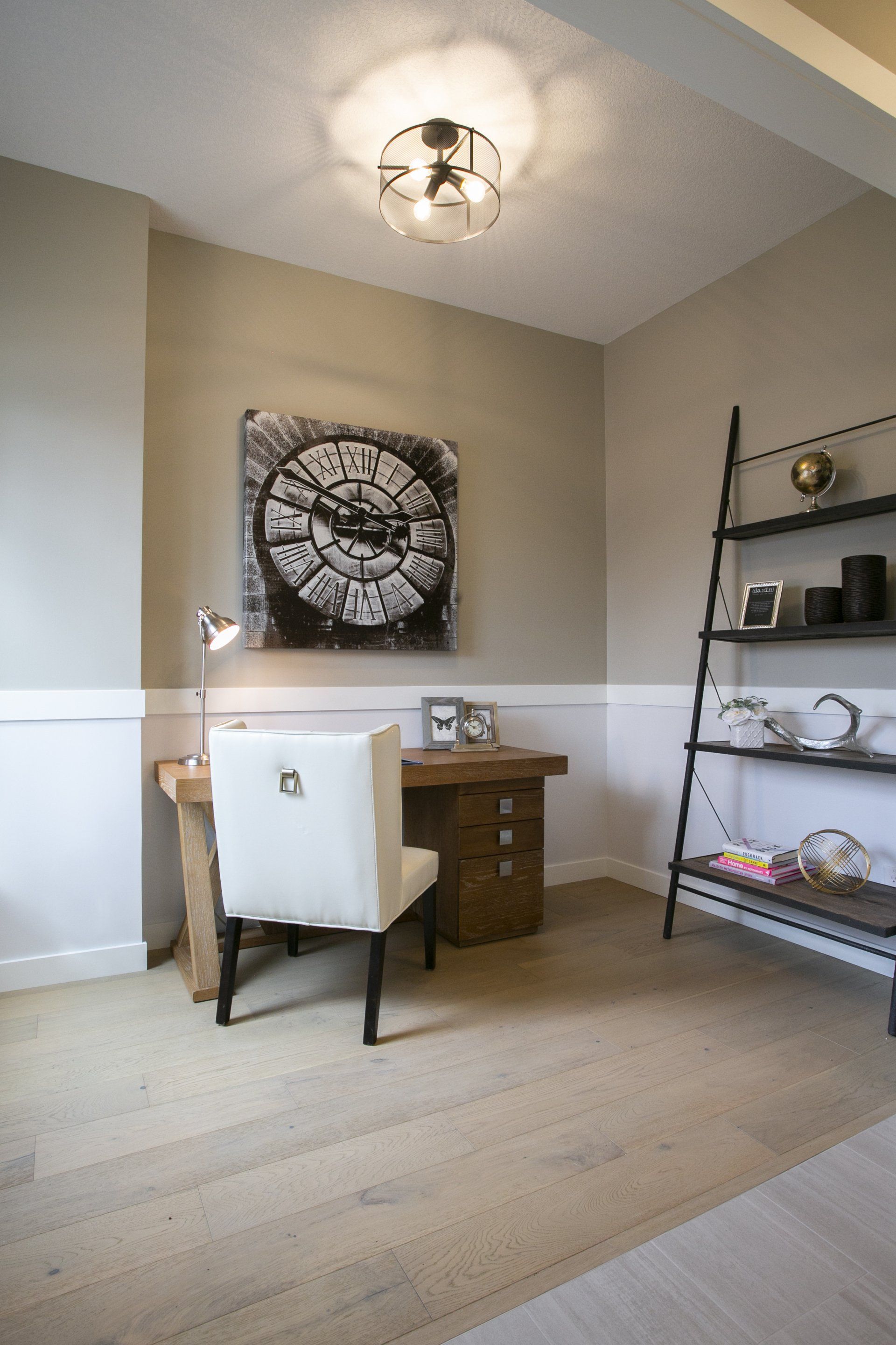 There is a clock on the wall above the desk in the room.