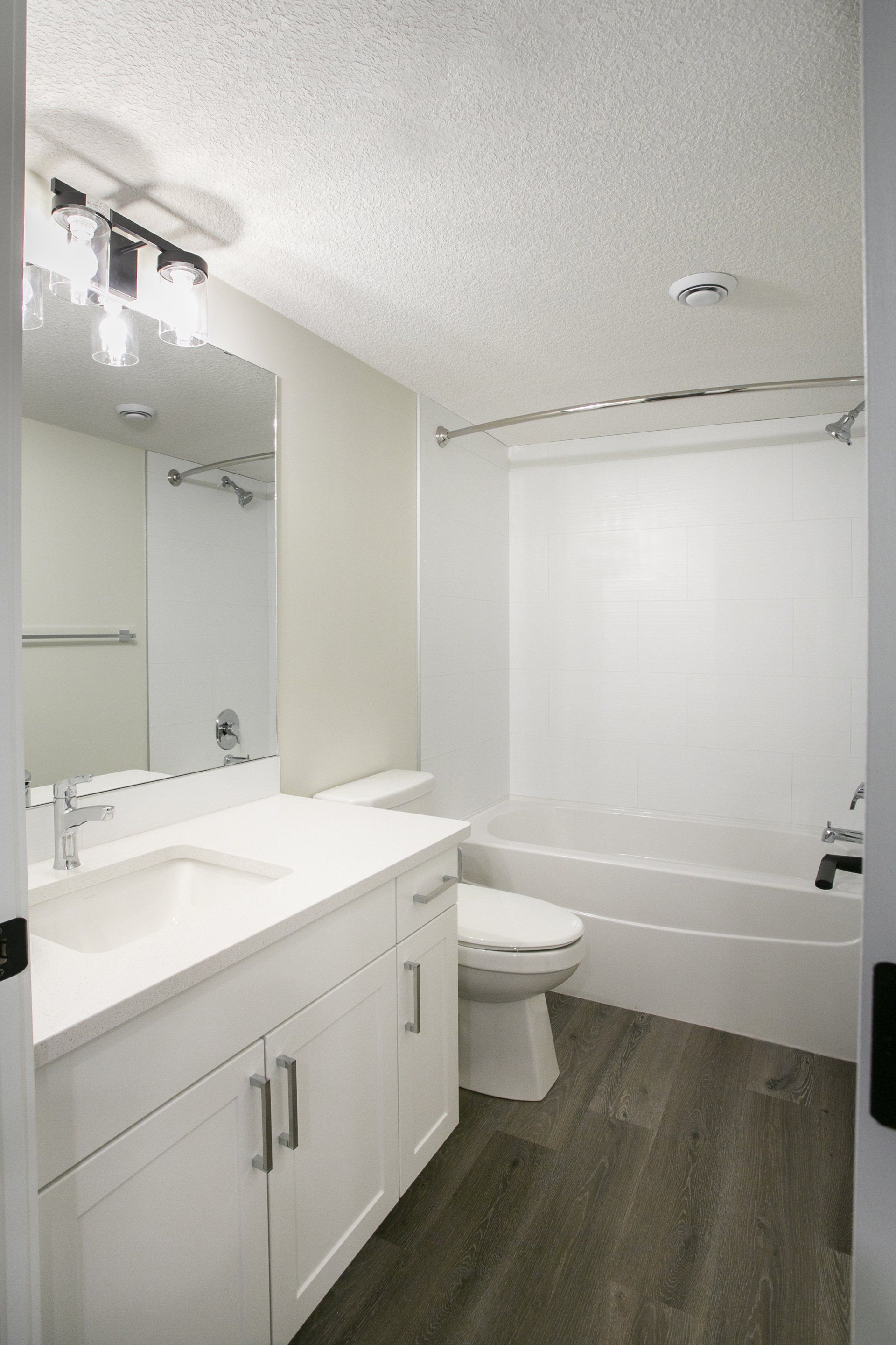 A bathroom with a sink , toilet , tub and mirror.