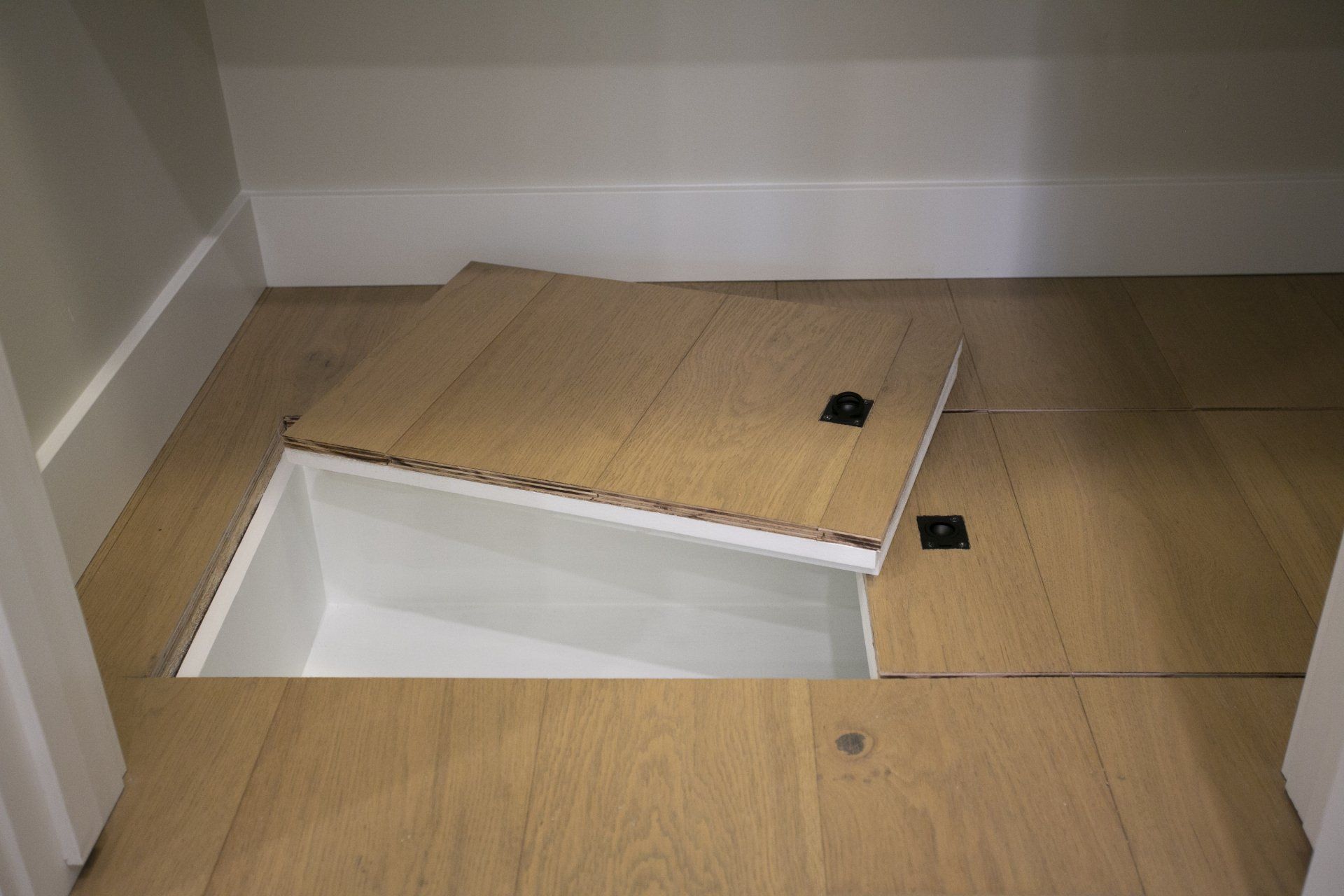 A wooden floor with a white box underneath it.