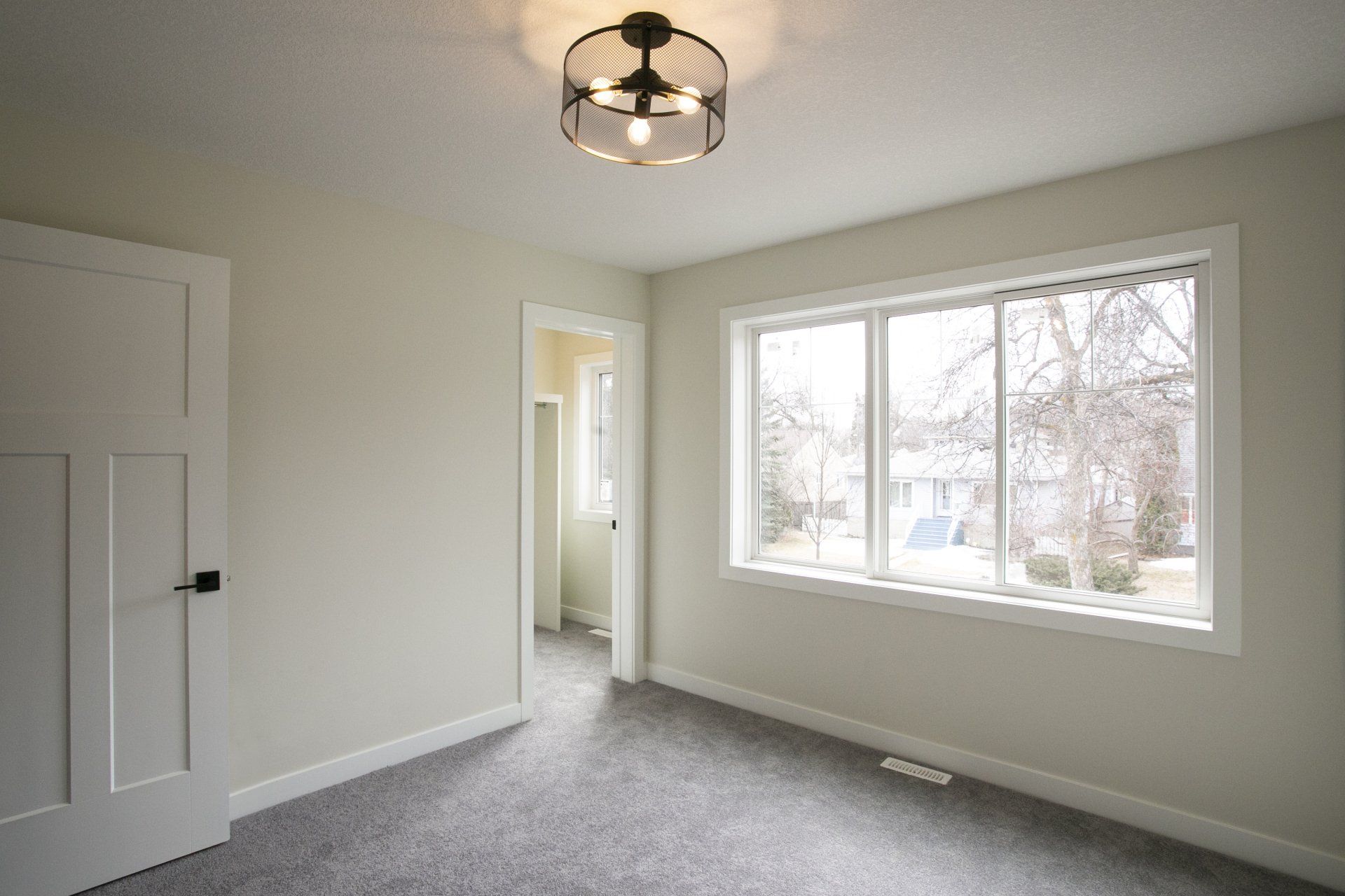An empty bedroom with a large window and a ceiling fan.