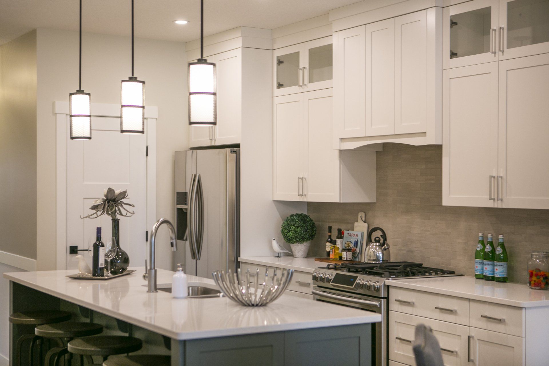 A kitchen with white cabinets , stainless steel appliances , and a large island.