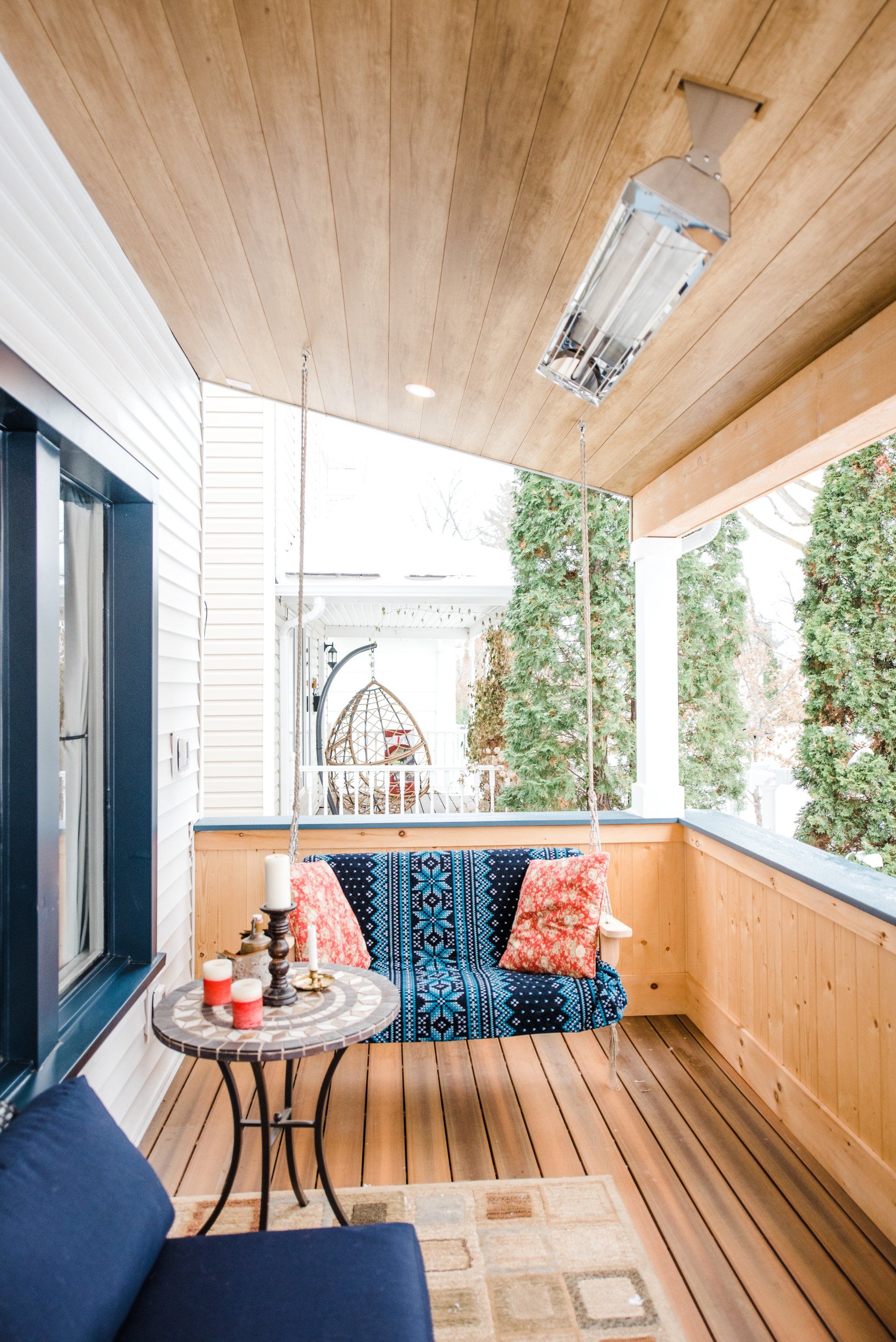 A porch with a couch , table and chairs on it.