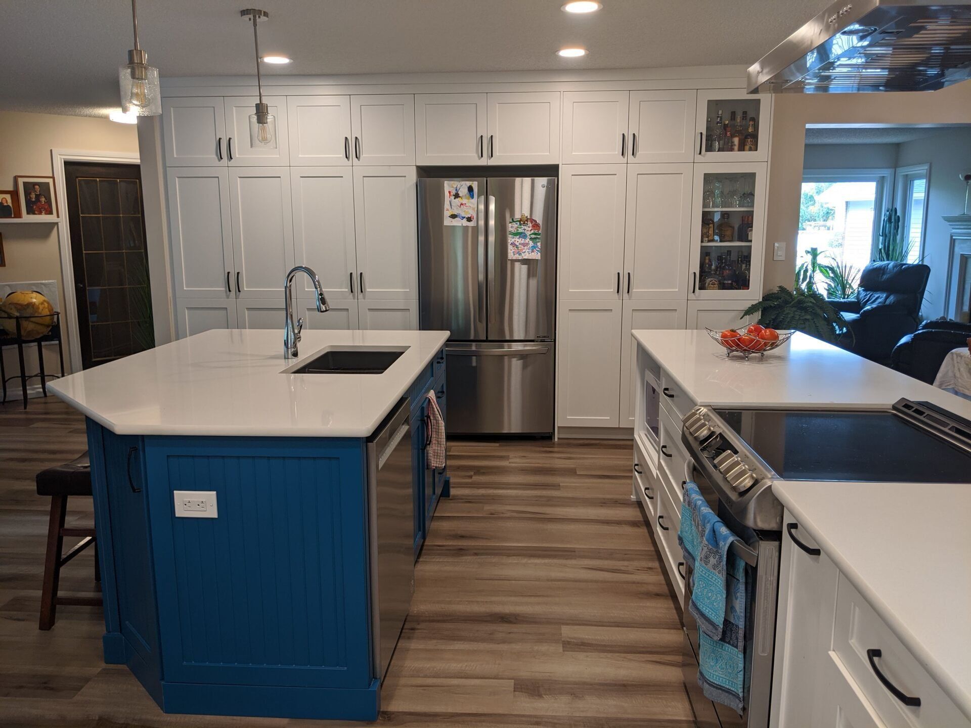 A kitchen with blue cabinets , white cabinets , stainless steel appliances and a large island.