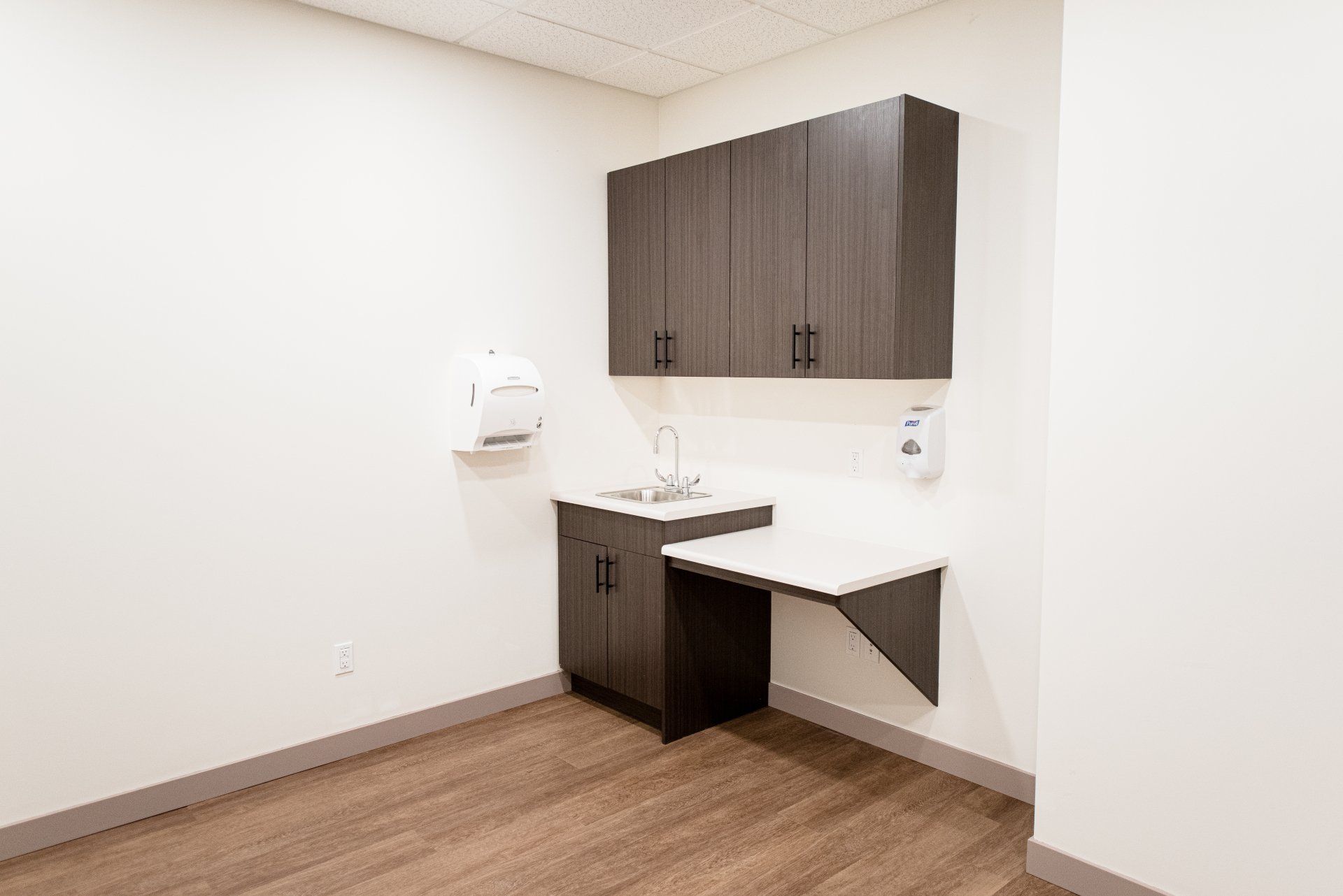 An empty room with a sink , cabinets , and a table.