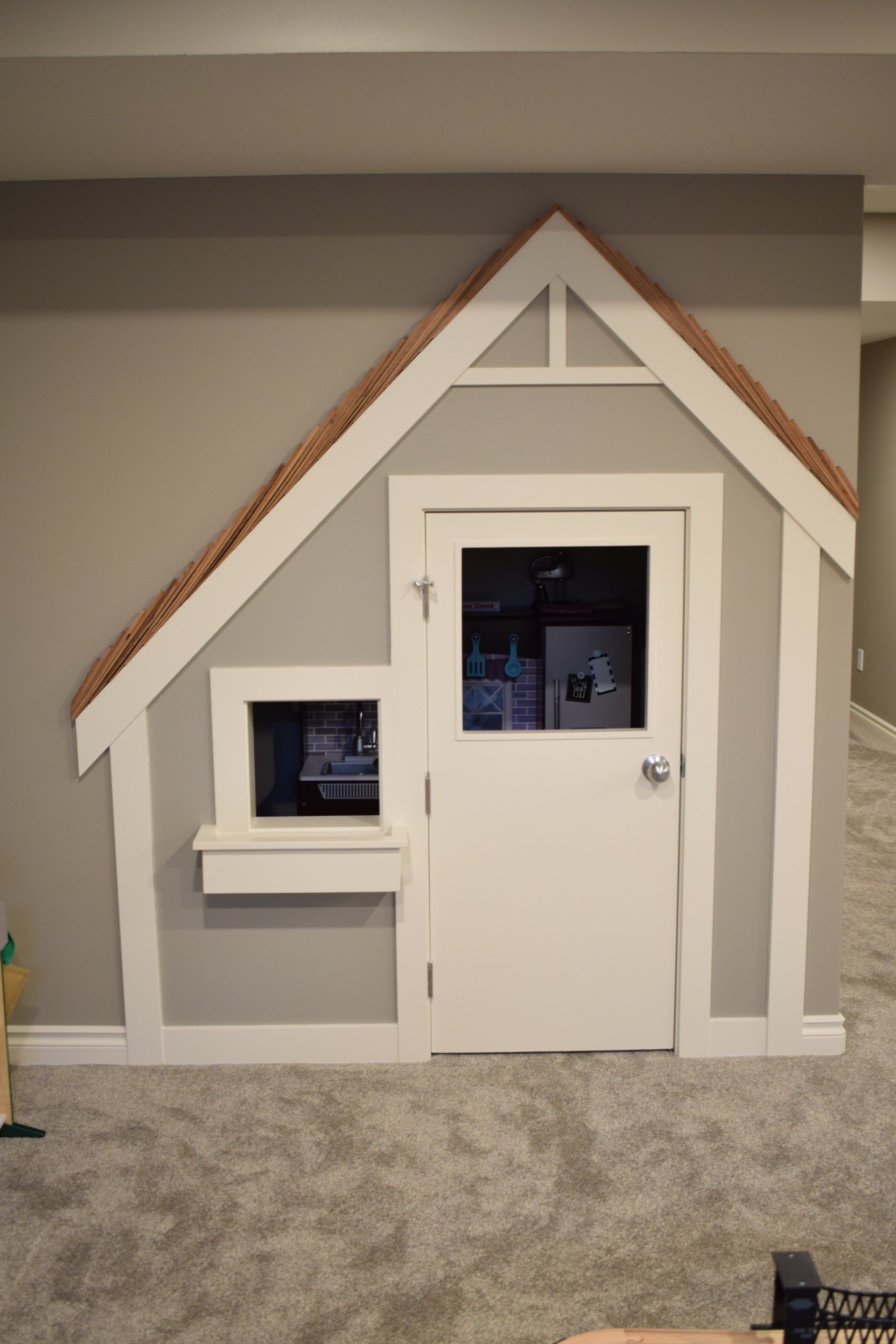 A playhouse is built into the wall of a room.