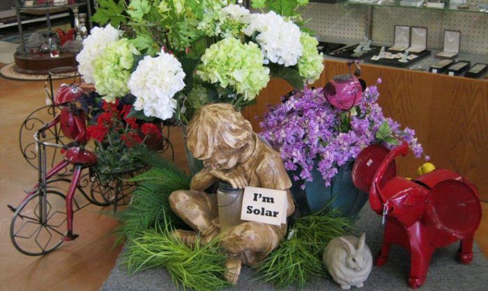Gold solar-themed display with flowers and a small statue holding an “I’m Solar” sign