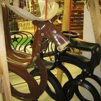 Side view of a brown and black mobility scooter in a store display with metal railings and shelves in the background