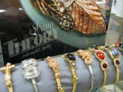 Decorative gold and jeweled bracelets displayed on a black velvet stand in a jewelry shop window