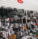 Retail display of assorted hanging tools and accessories on a store wall, with an OXO sign overhead