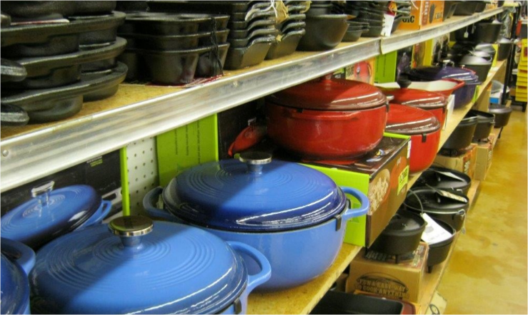 Store shelves lined with colorful enameled cooking pots and pans, mostly blue and red lids