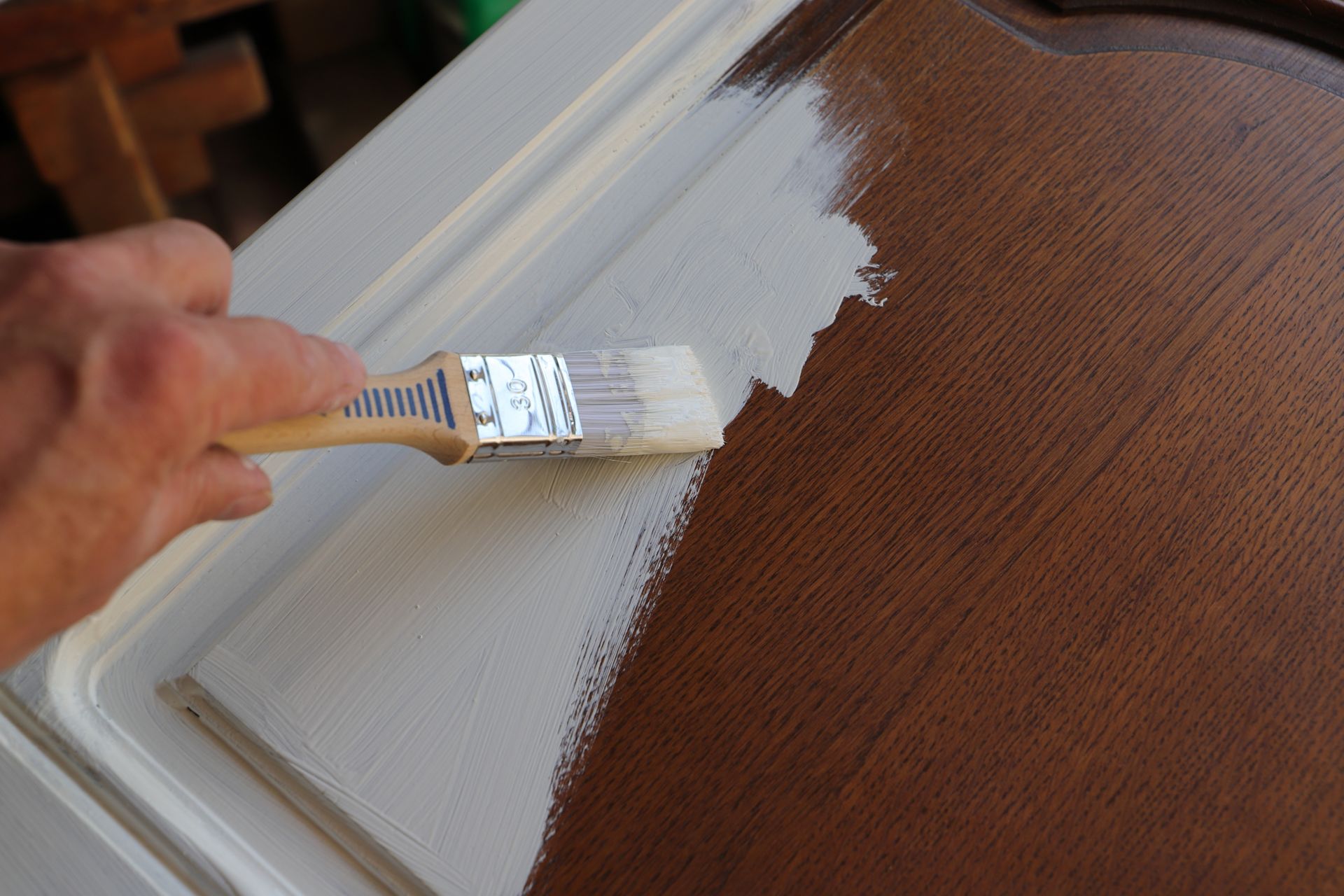 A brown kitchen cabinet undergoing a stunning makeover as it gets coated with white chalk paint, adding a fresh and bright touch to the space.