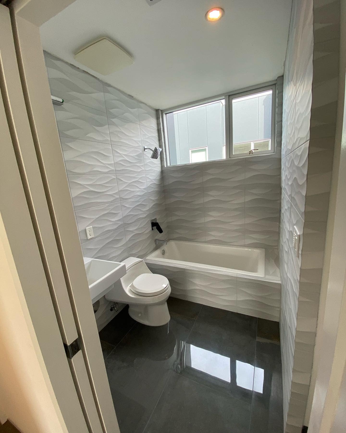 A bathroom with a toilet , sink , tub and window.
