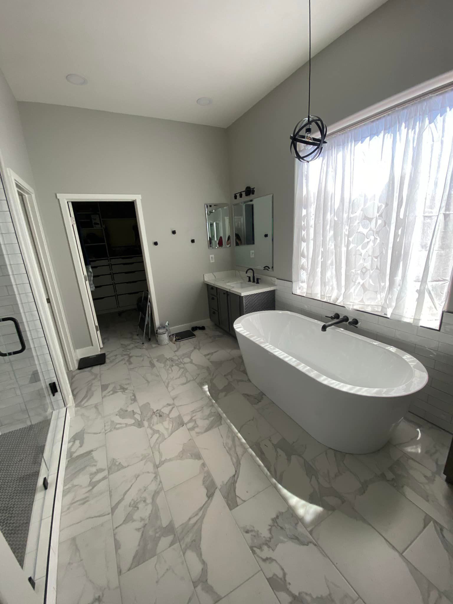 A bathroom with a tub , sink , mirror and window.