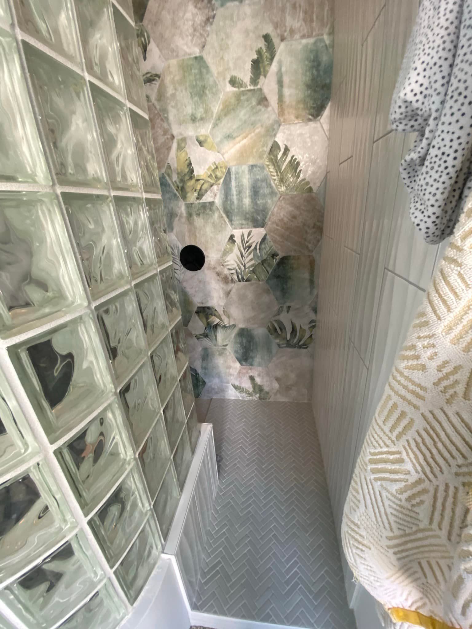 A bathroom with a floral wallpaper on the wall and a glass block wall.