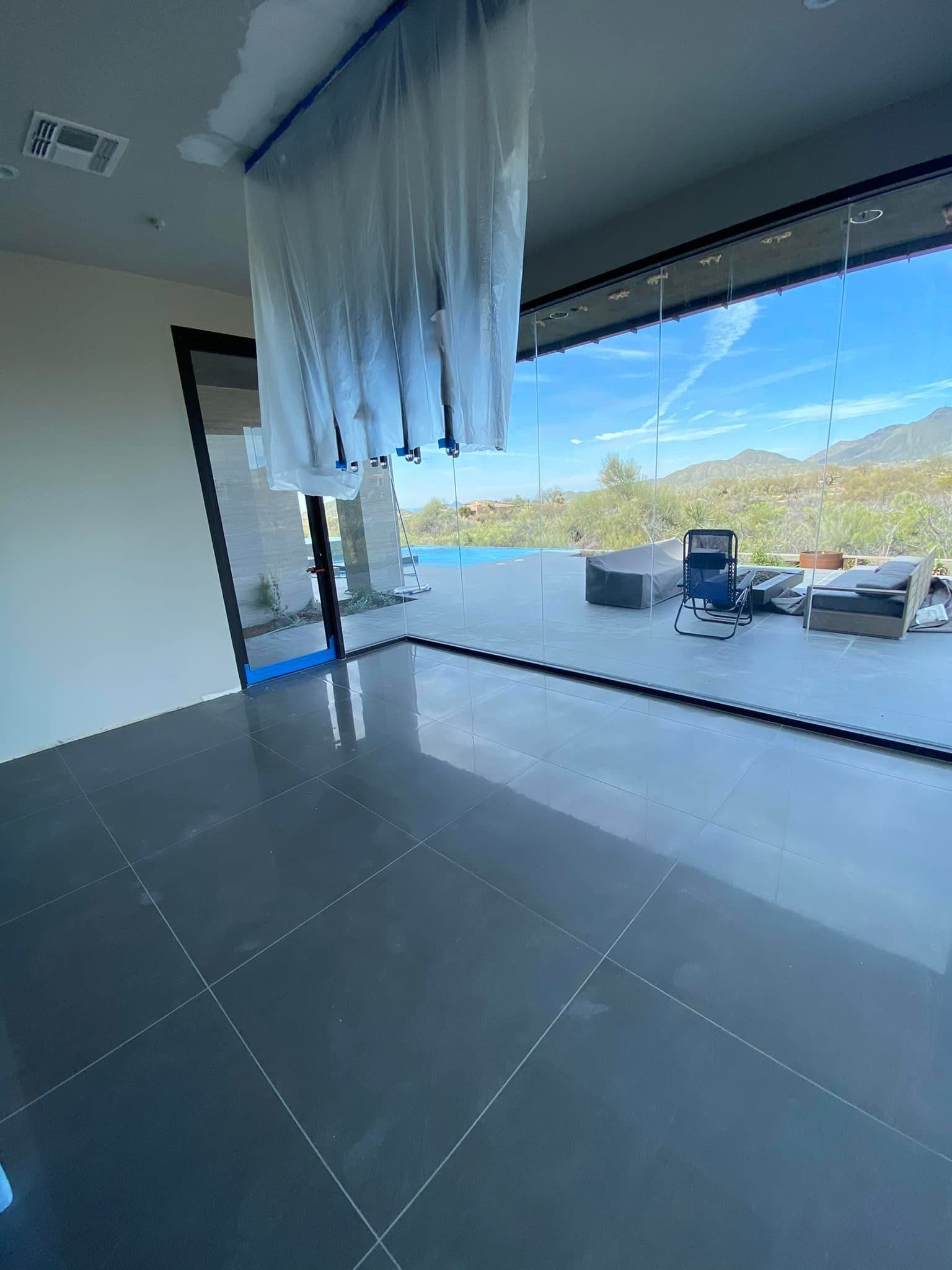 An empty room with a large window and a chandelier hanging from the ceiling.