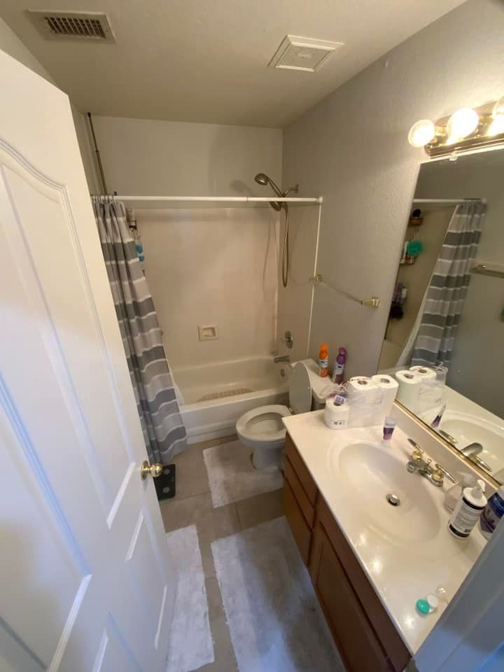 A bathroom with a sink , toilet , shower and mirror.