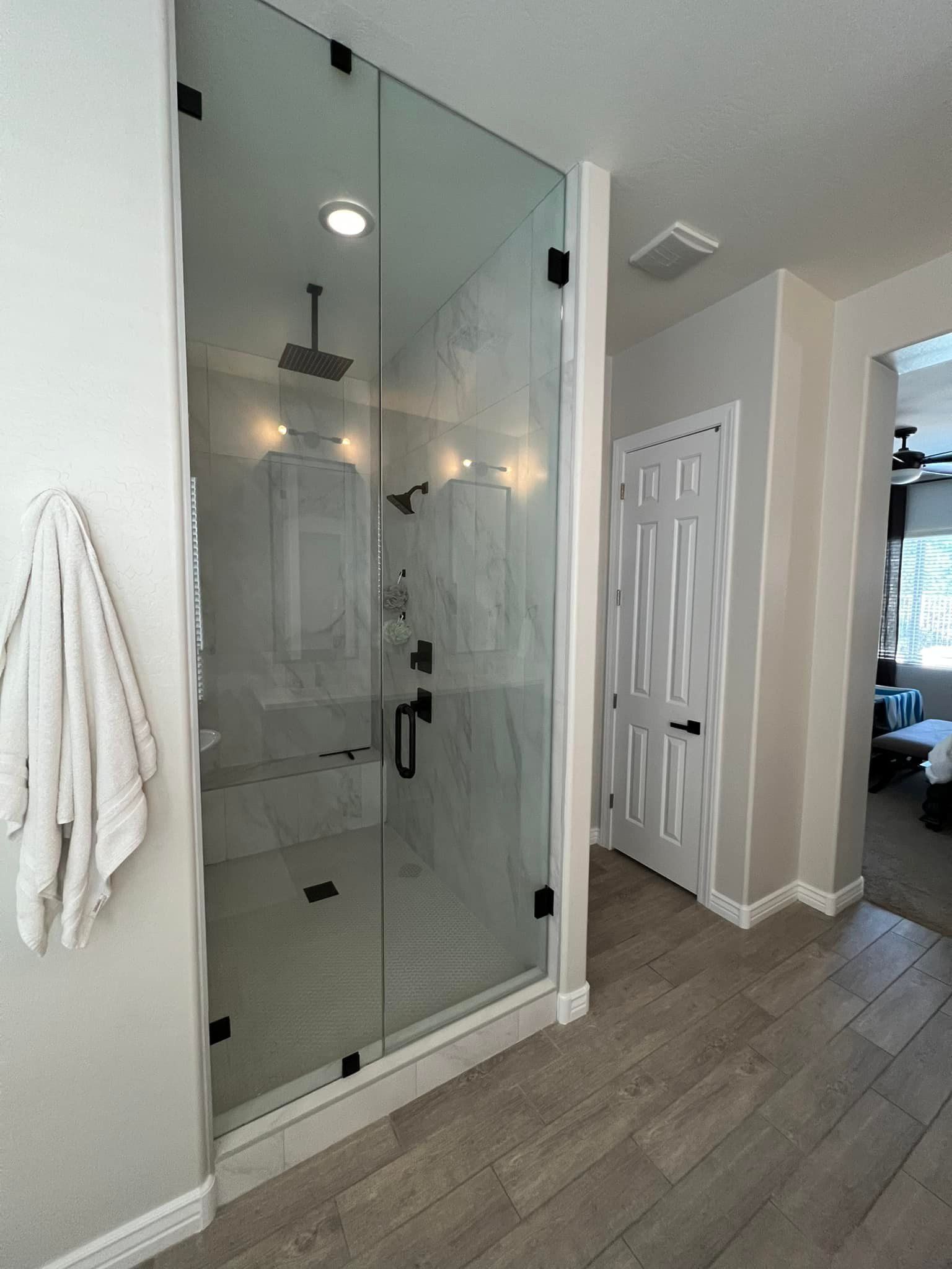 A bathroom with a walk in shower and a towel hanging on the wall.