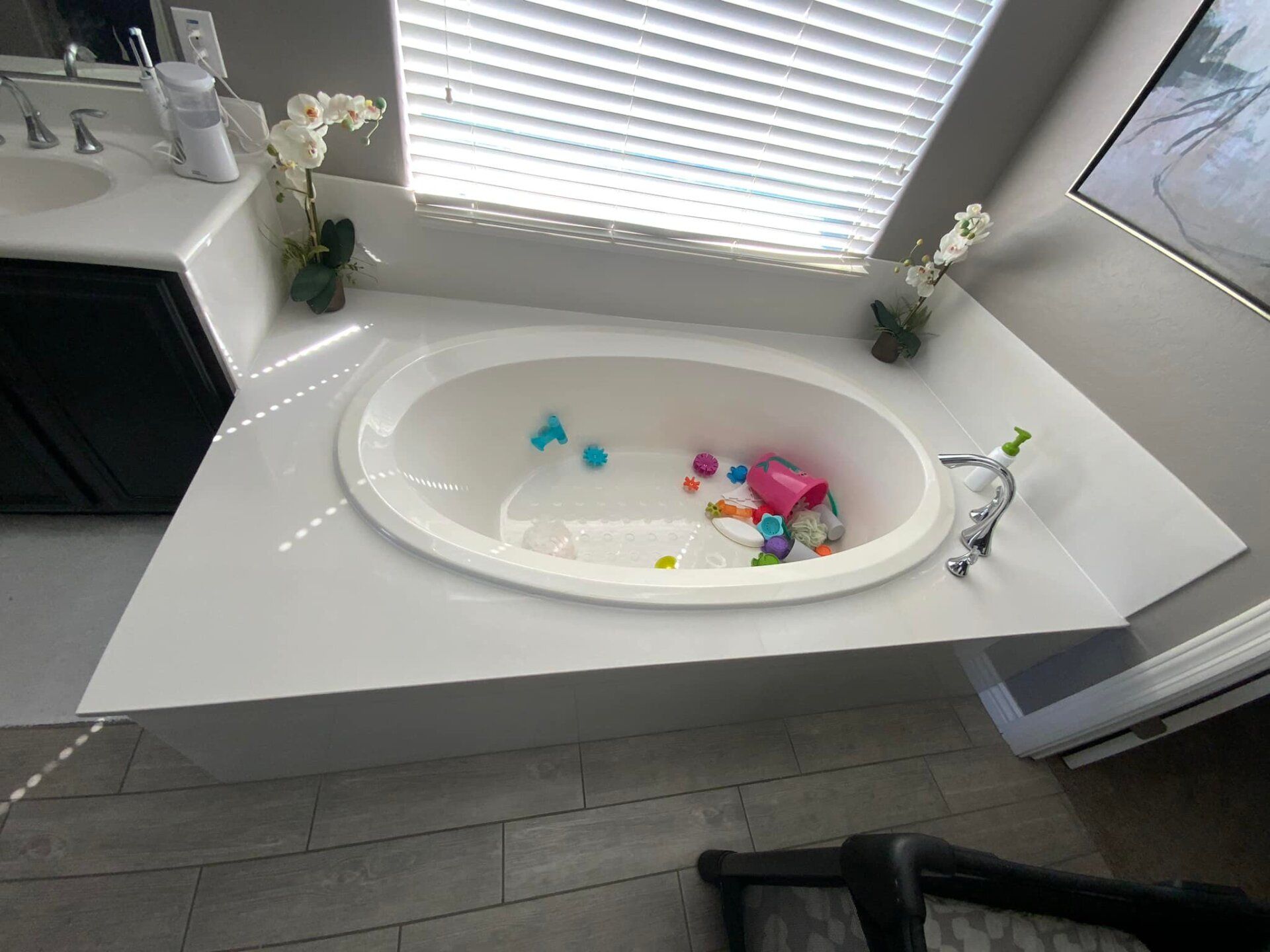 A bathtub filled with toys in a bathroom next to a window.