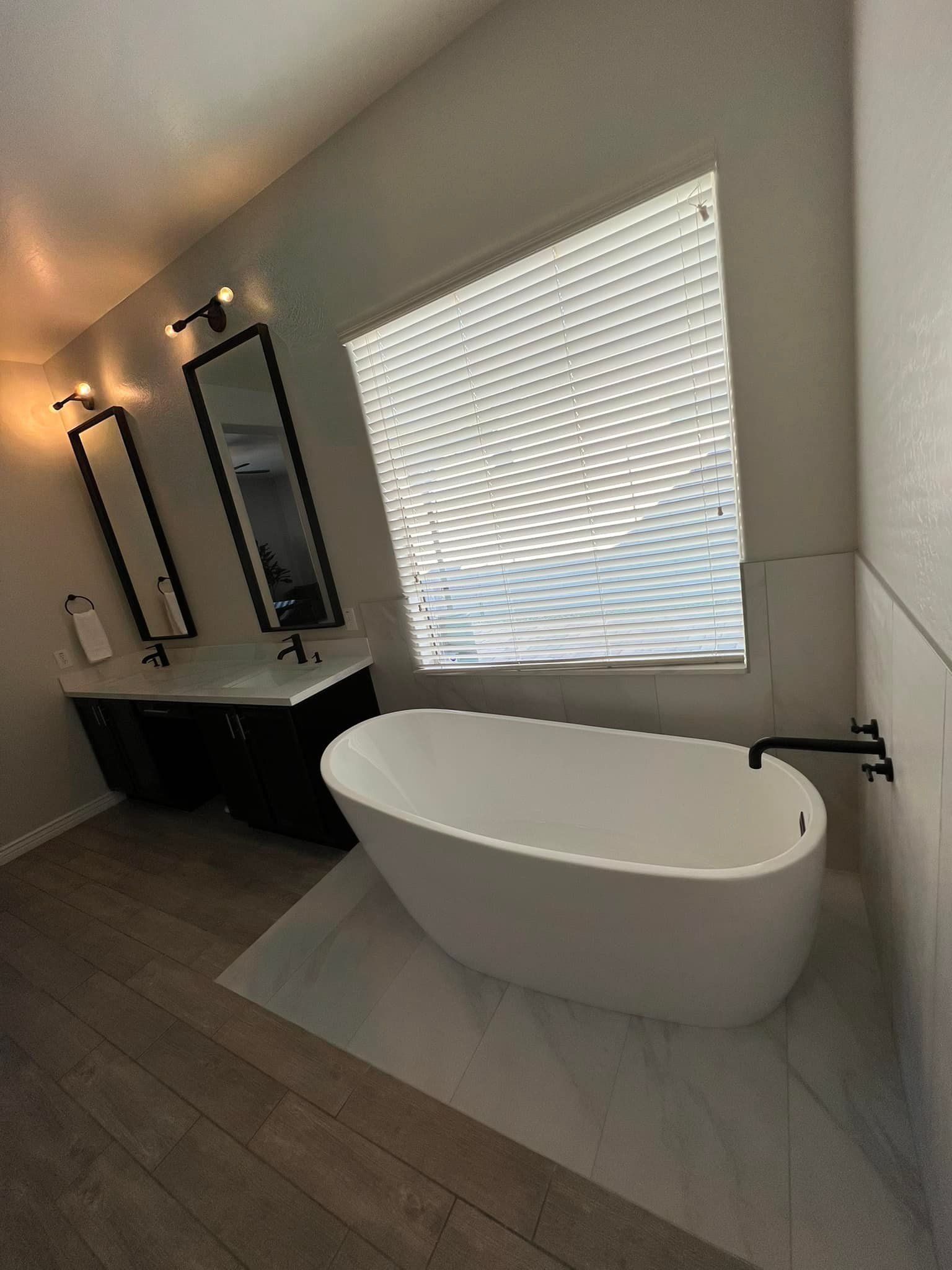 A bathroom with a bathtub , sinks , mirrors and a window.