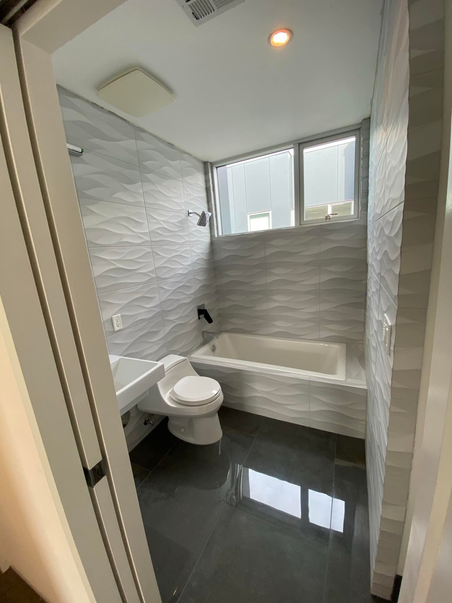 A bathroom with a toilet , sink , tub and window.