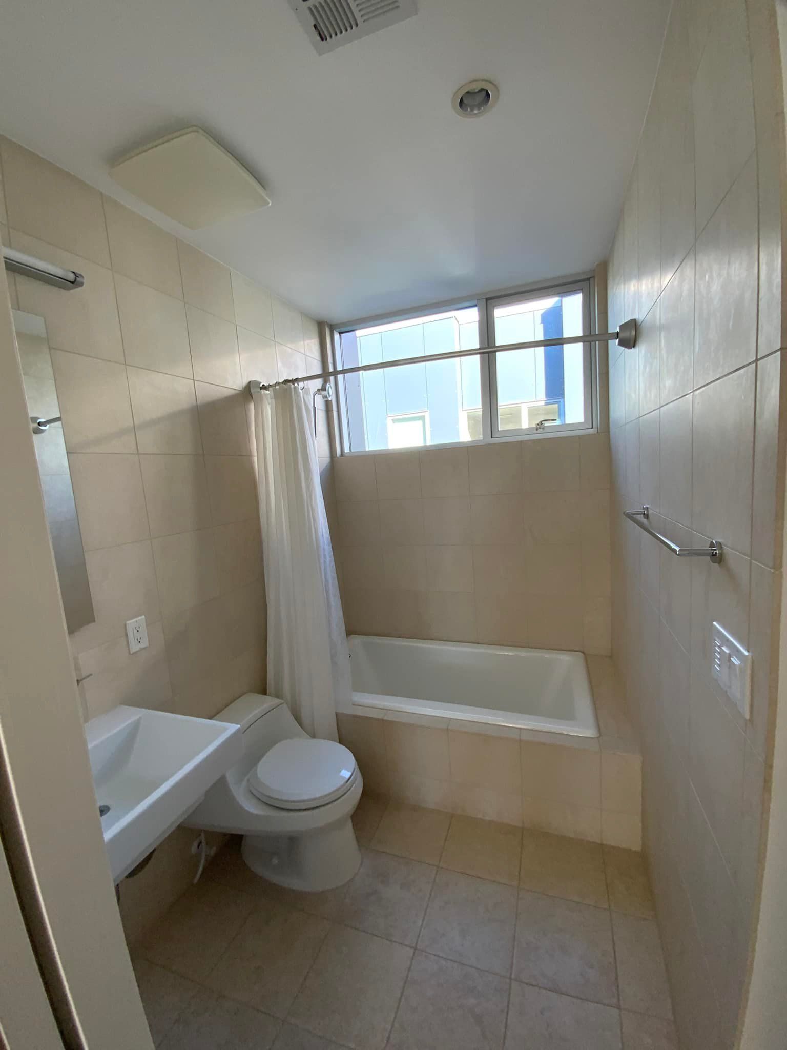 A bathroom with a toilet , sink , tub and window