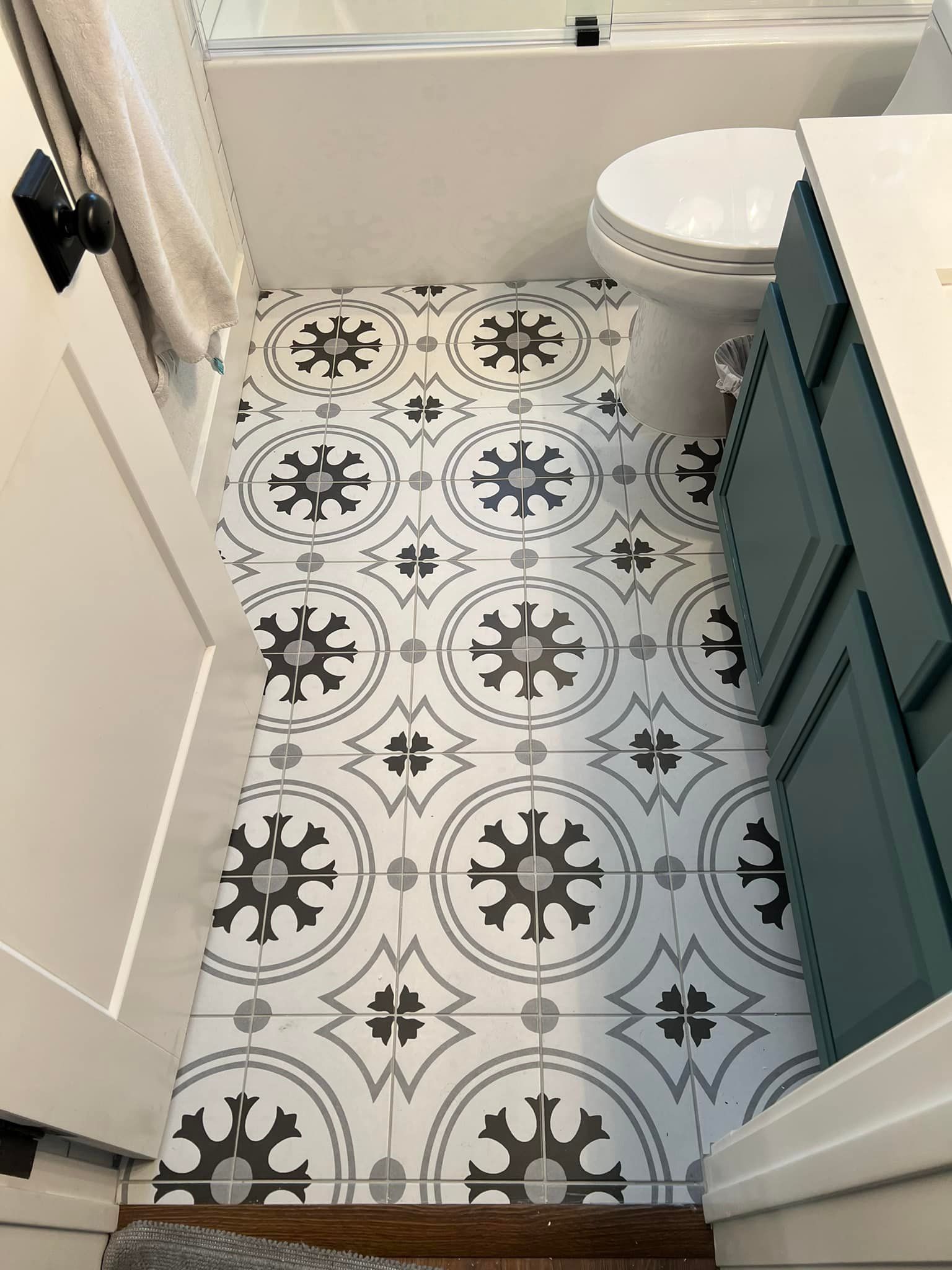 A bathroom with a toilet , sink , and bathtub . the floor is tiled with a black and white pattern.