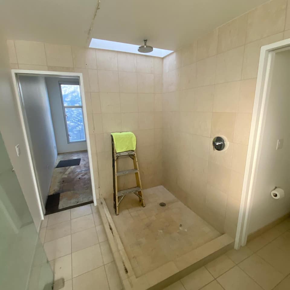 A bathroom with a shower and a ladder in it.
