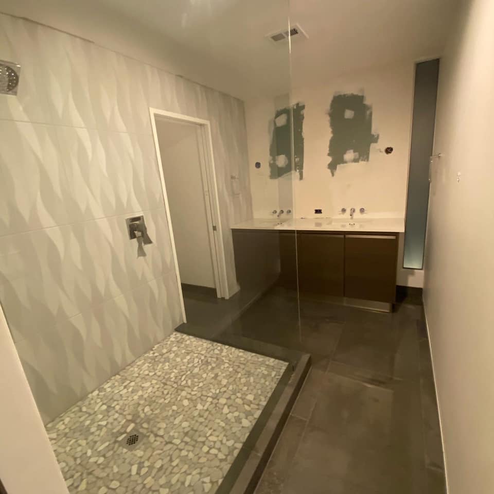 A bathroom with a walk in shower and a sink
