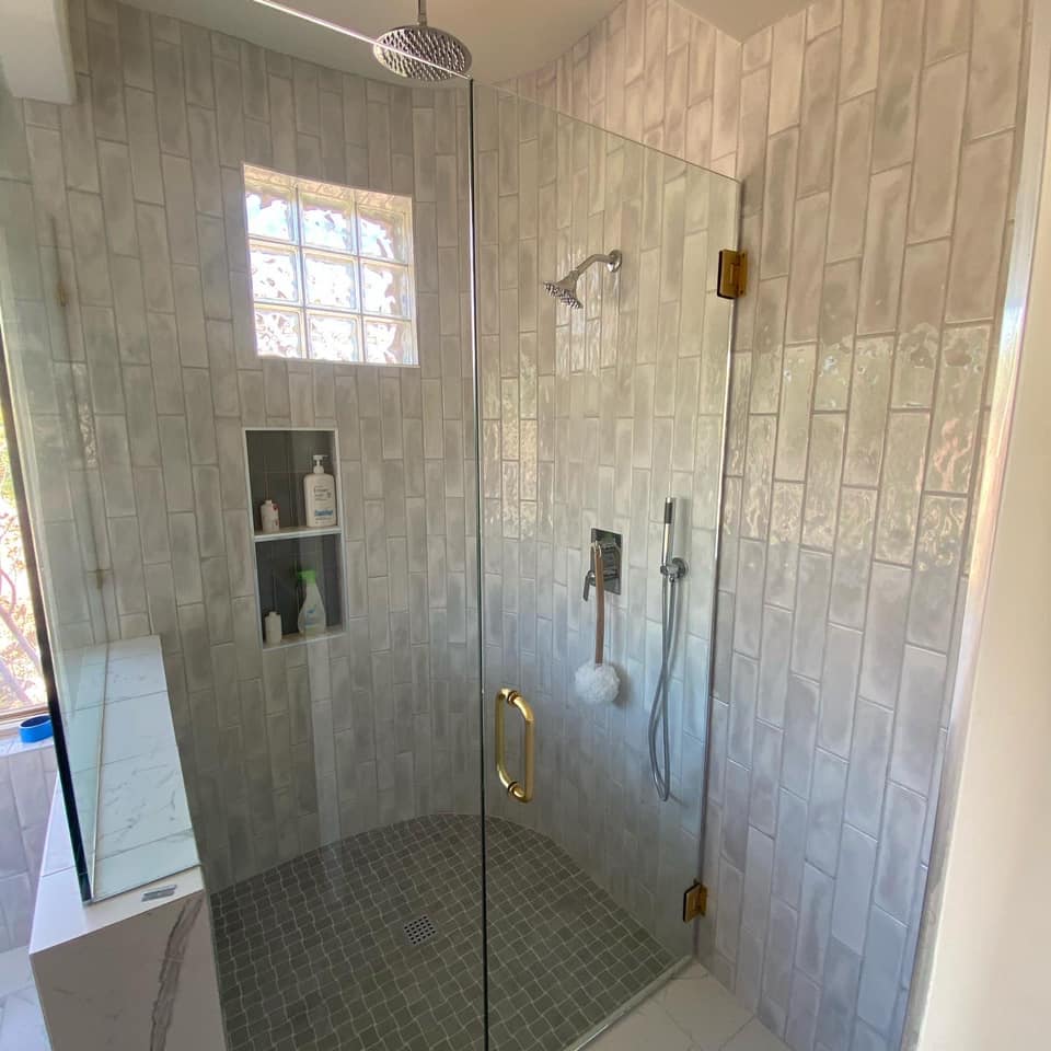 A bathroom with a walk in shower with a glass door.
