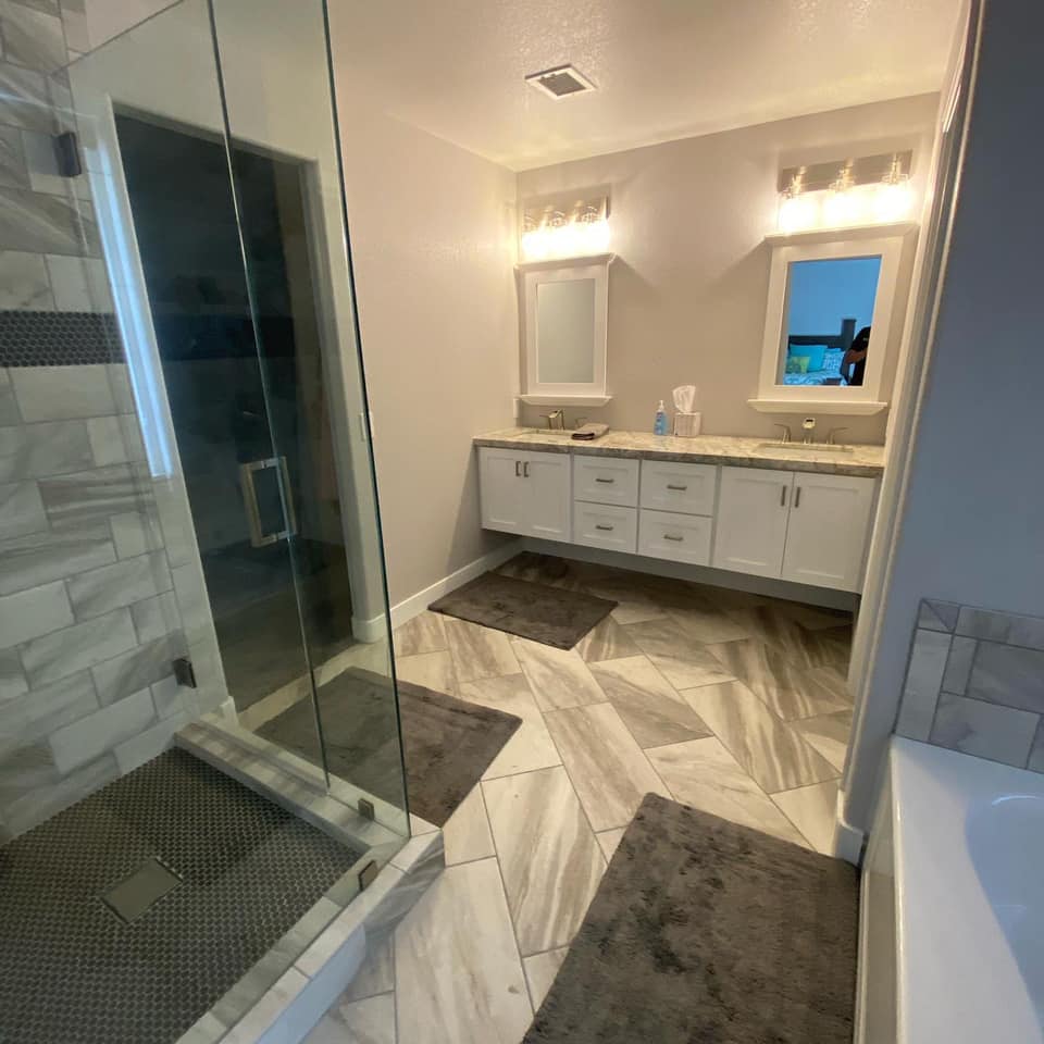 A bathroom with two sinks and a walk in shower.