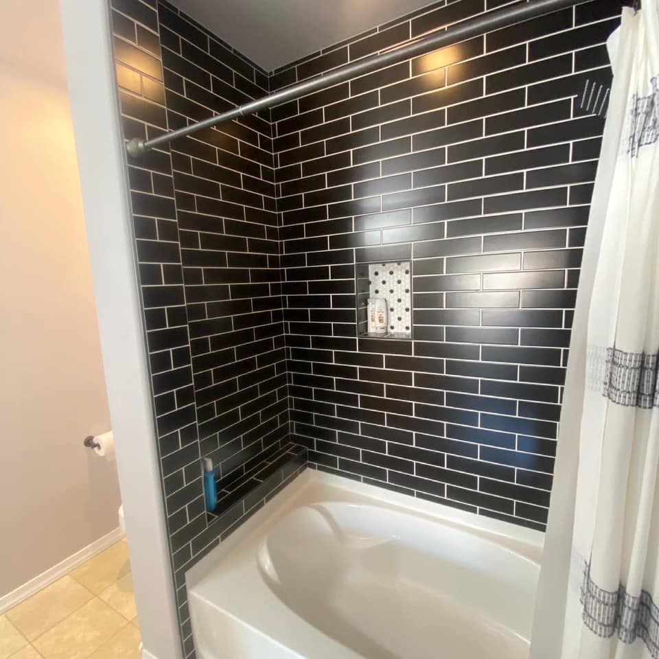 A bathroom with black brick walls and a bathtub