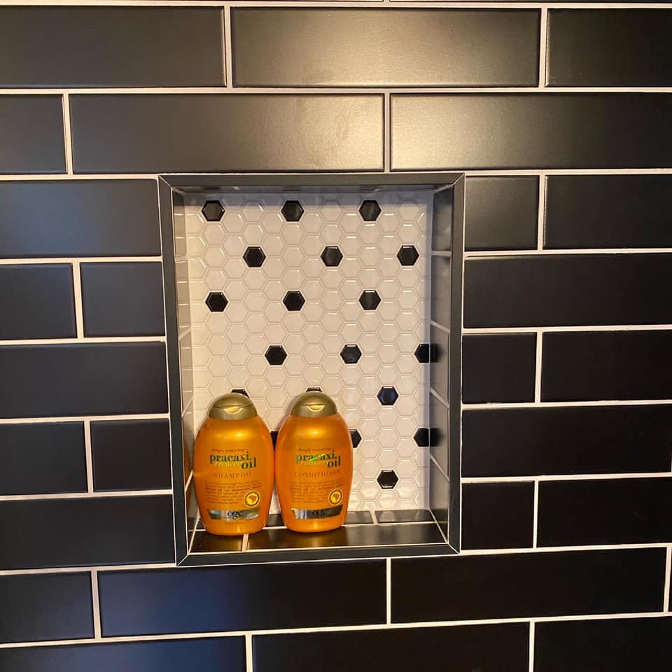 Two bottles of shampoo and conditioner are sitting in a shower niche.